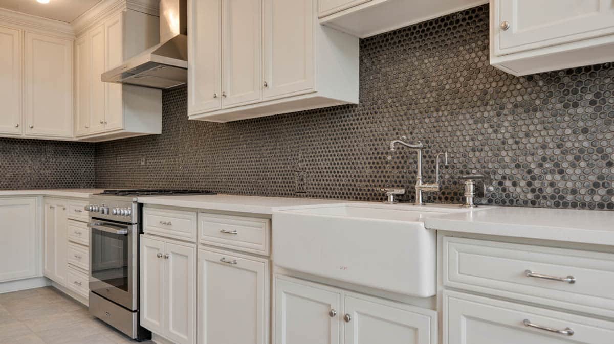 White kitchen with black hexagonal mosaic tile backsplash and clean countertops
