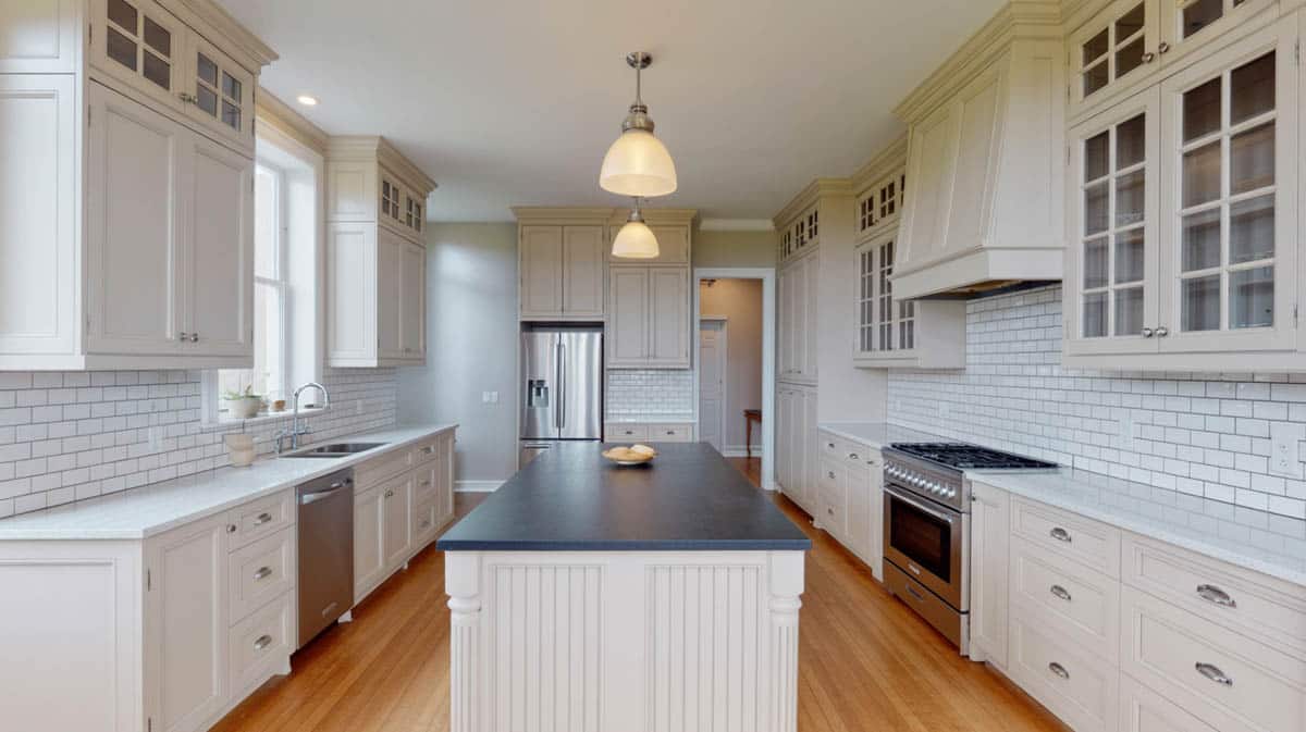 Classic kitchen with white cabinets, black soapstone island and white tile backsplash