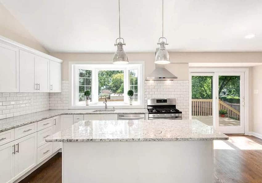Kitchen with bay window, white cabinets, white subway tile and granite countertops