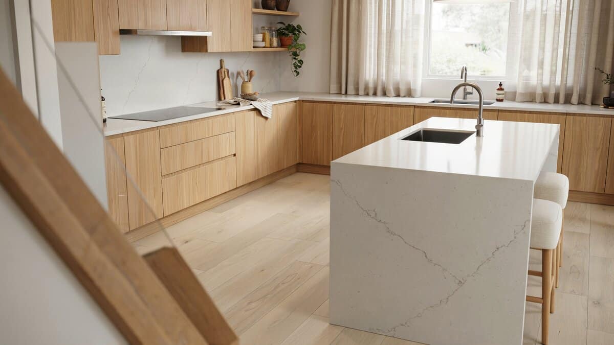 Pale engineered wood floor in a kitchen with light cabinets and a quartz island
