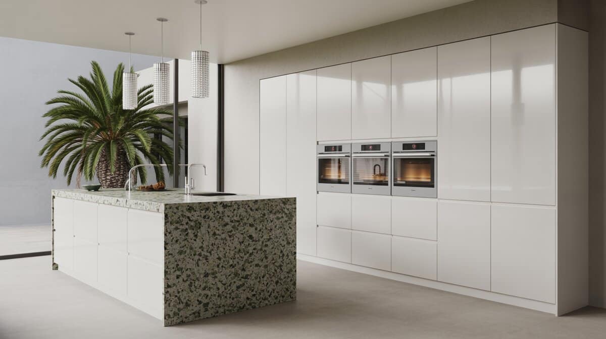 Minimalist white kitchen with a speckled green granite waterfall island and palm tree accent