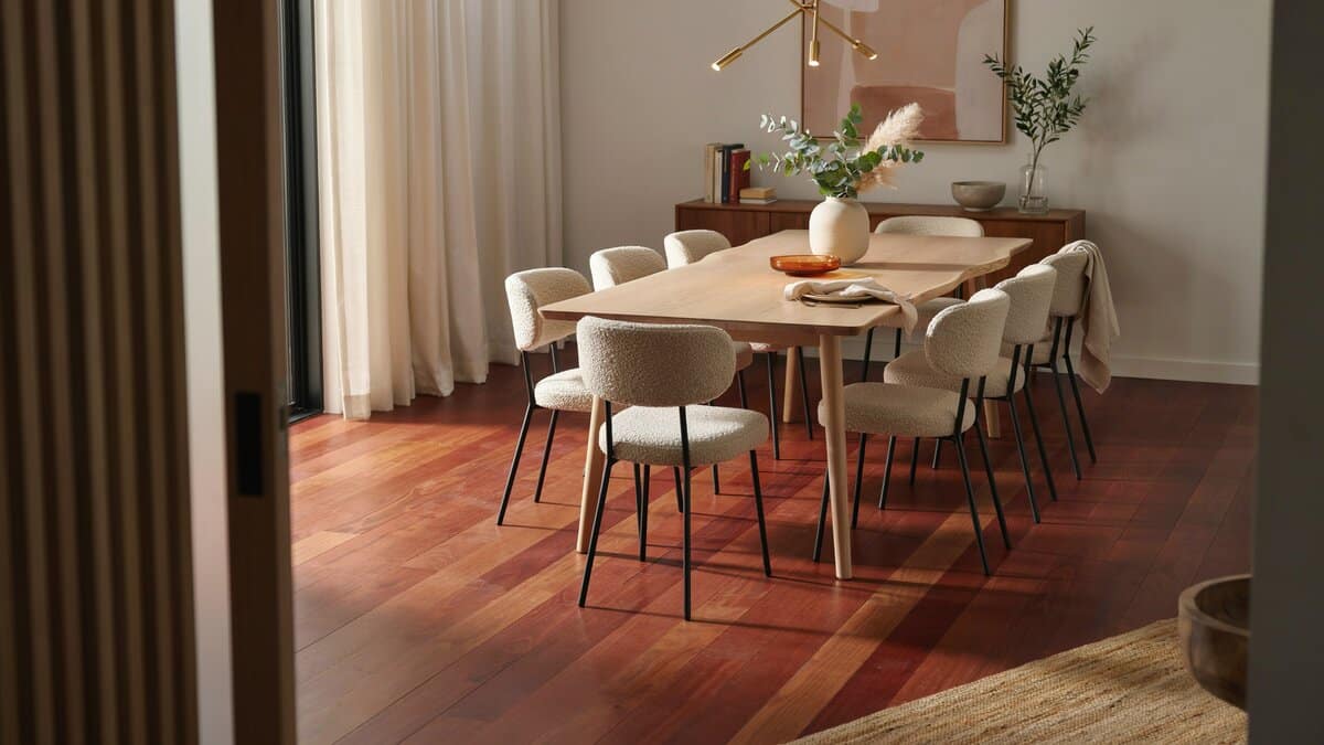 Red oak flooring under a wood dining table ringed with curved white chairs