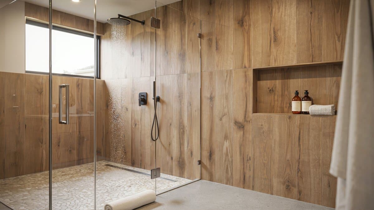 Walk-in shower with wood-look porcelain tile walls and frameless glass panel