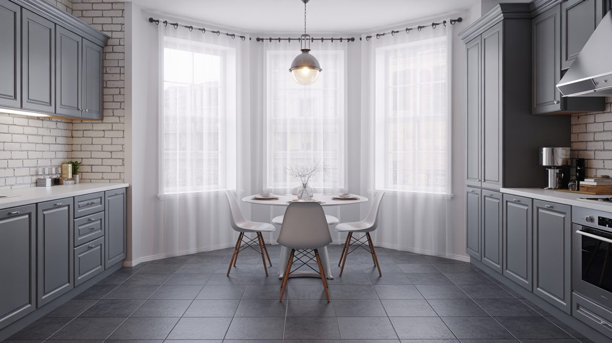 Gray cabinet kitchen with white exposed brick, sheer-curtained bay window, and round dining table with Eames chairs