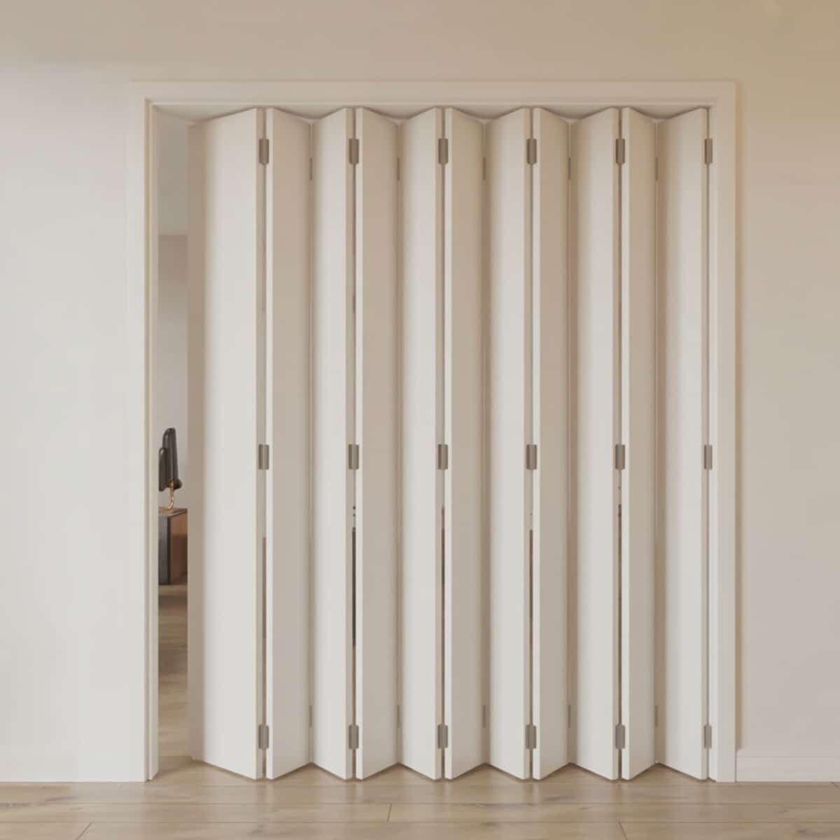 White folding accordion door spanning a hallway with light wood flooring