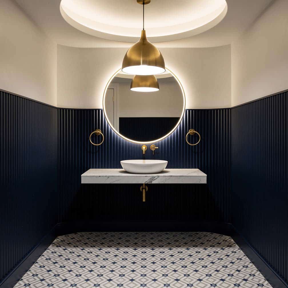 Bathroom powder room accented with a circular ceiling feature and large central chandelier.