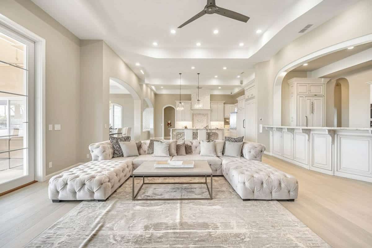 Room with curved ceiling and tufted sectional couch and open concept kitchen