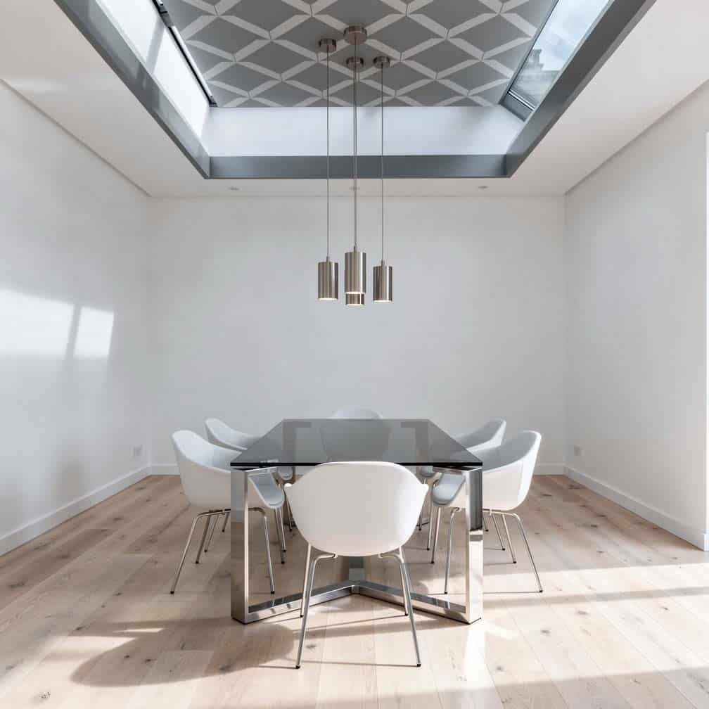 Gray and white geometric ceiling design above a smoked glass dining table.