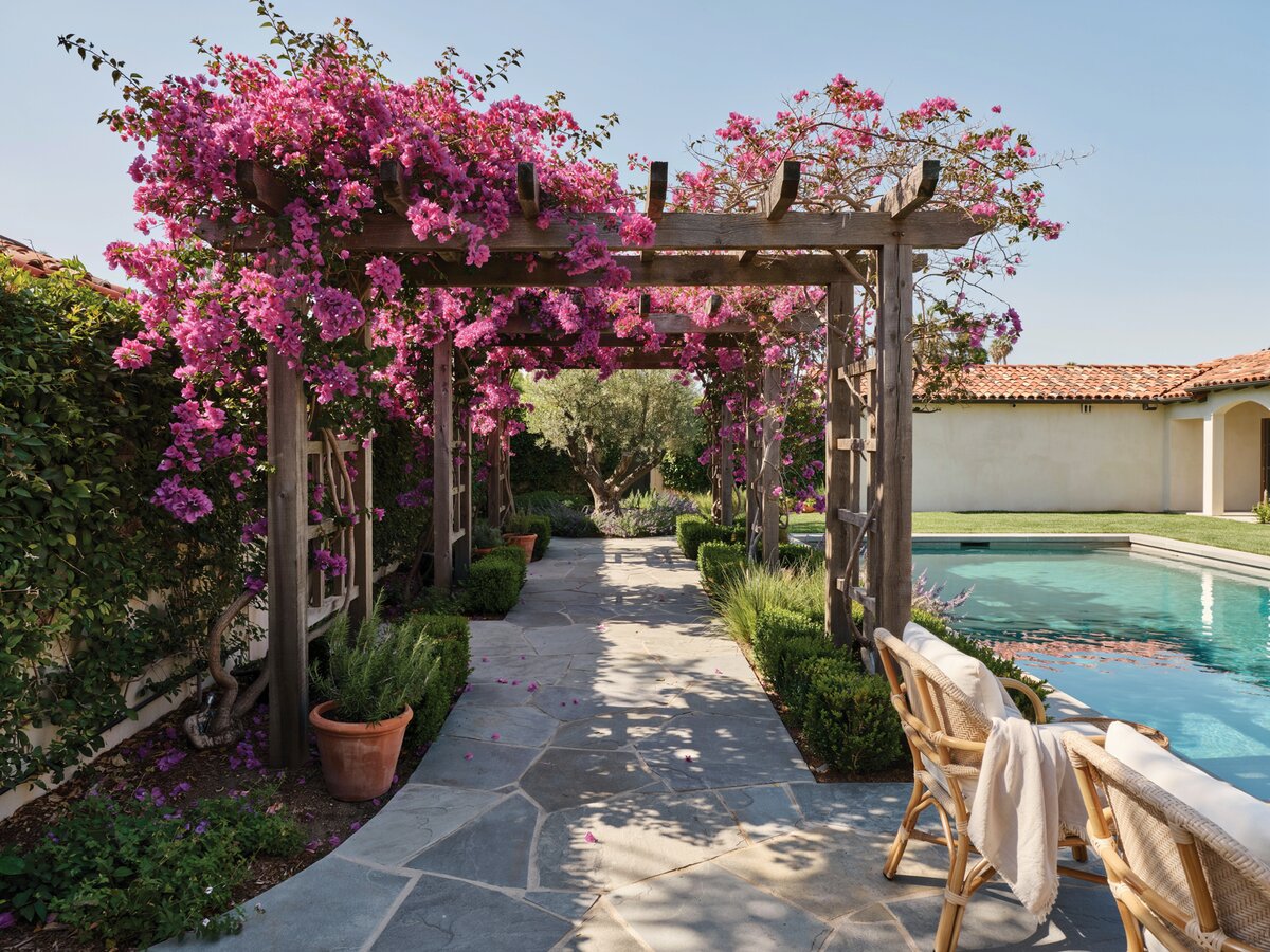 Granite flagstone pathway around a pool with rustic wood arbors and purple bougainvillea in bloom
