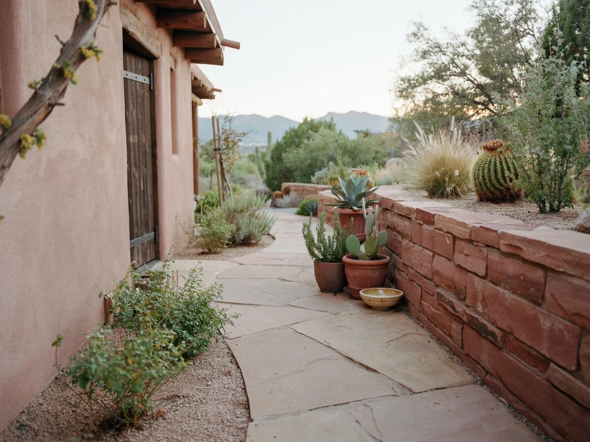 Irregular flagstone path through a Southwest Santa Fe garden with a red sandstone wall and adobe home