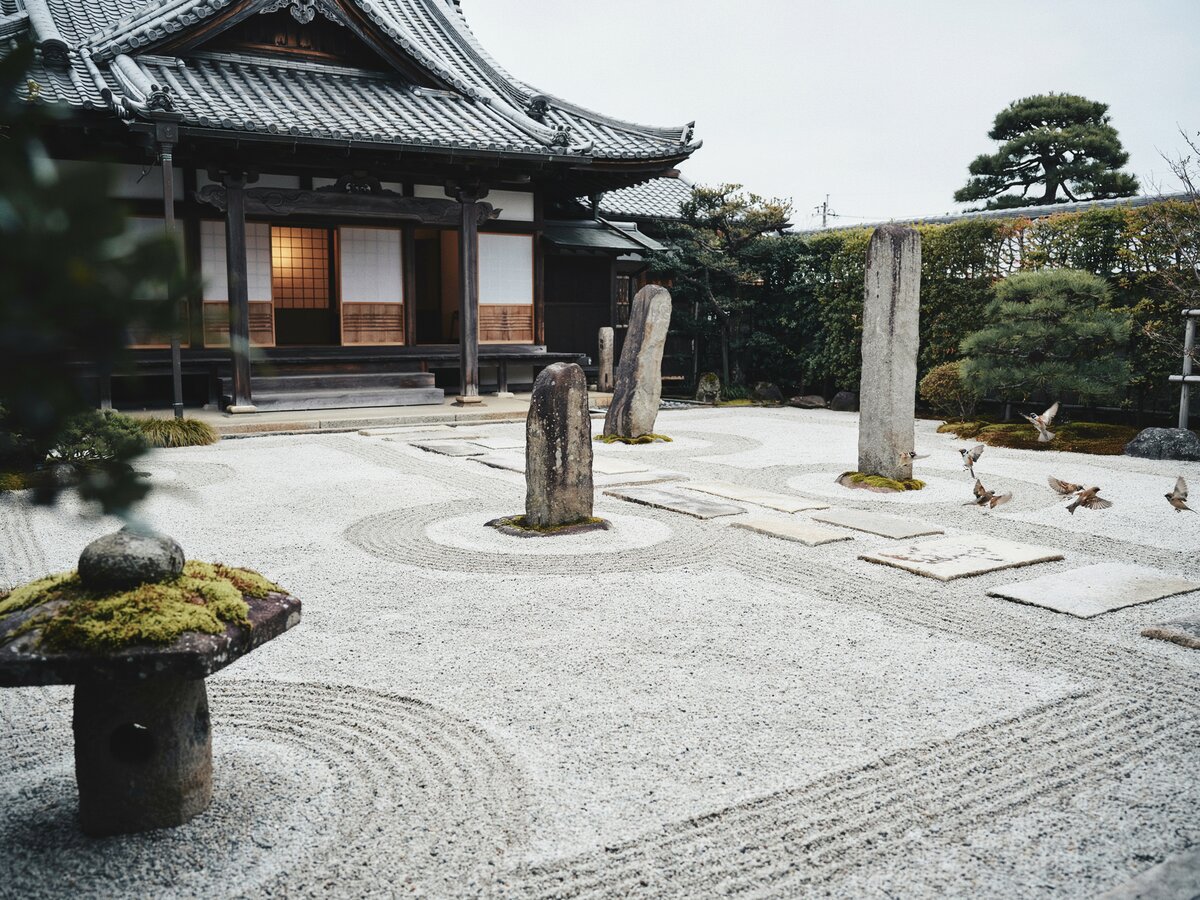 Japanese zen rock garden with perfectly raked white gravel standing stones and square stepping pavers