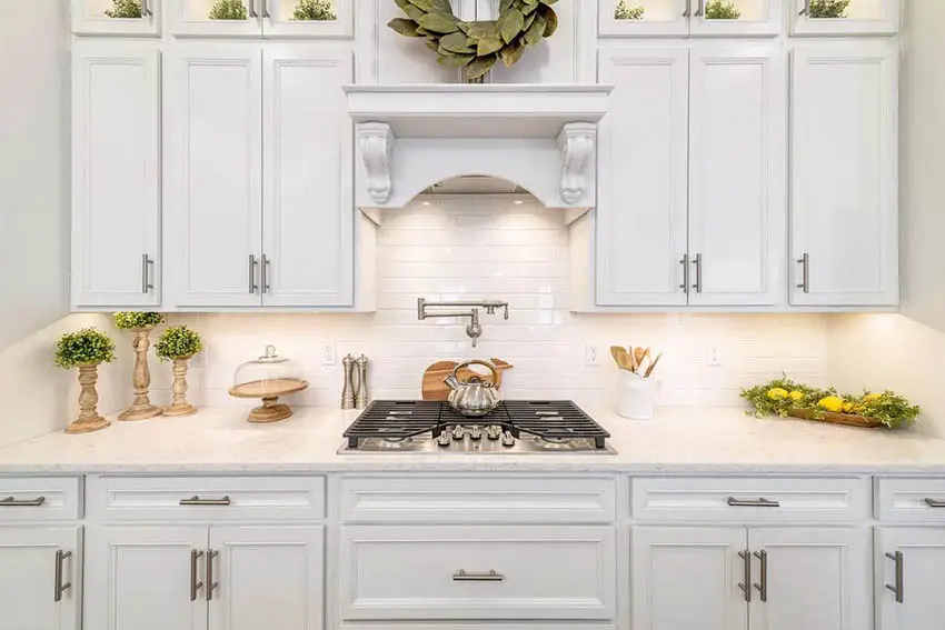 Kitchen countertop with outlets, white cabinets, subway tile backsplash and range hood