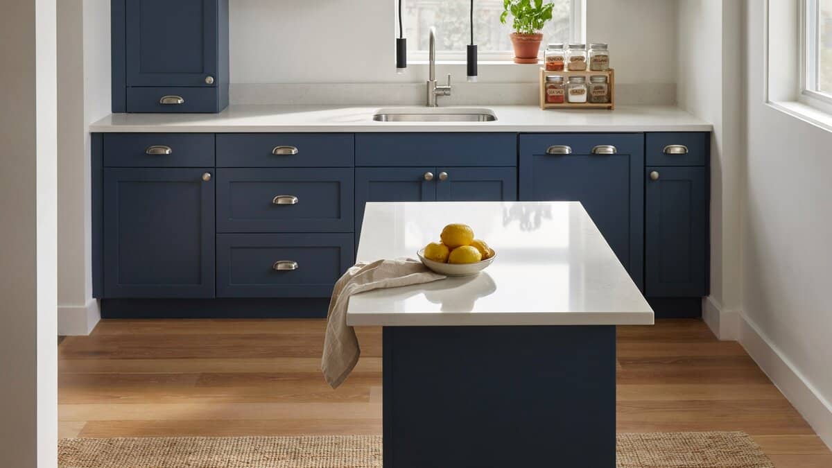 Spice jars displayed on white island counter in kitchen with blue cabinets