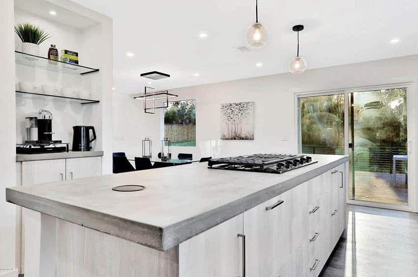 Kitchen with concrete countertop island and bleached wood cabinets