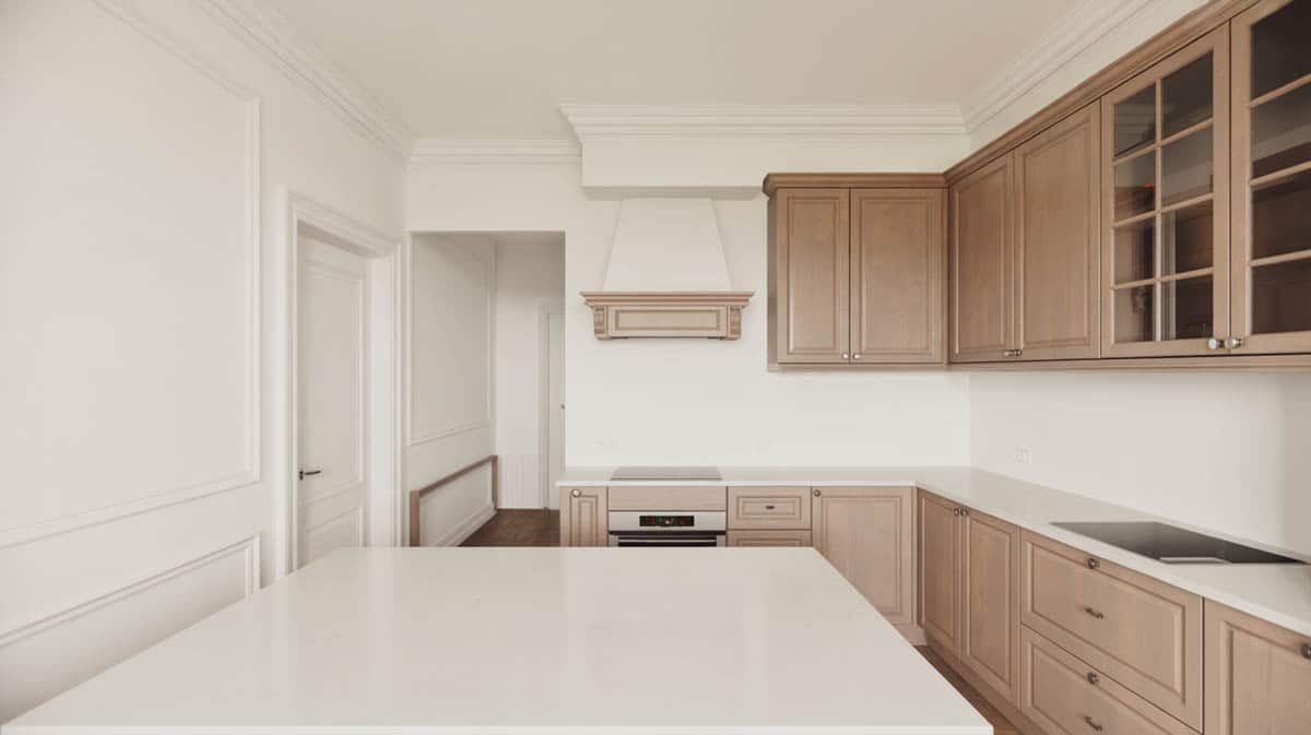 Modern kitchen with white walls, white crown molding, and light beige stained wood cabinets