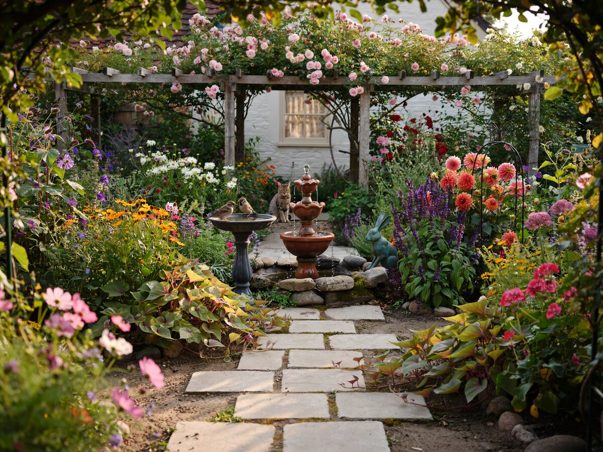 Square concrete stepping pavers through a vibrant cottage garden with a decorative fountain and colorful perennials
