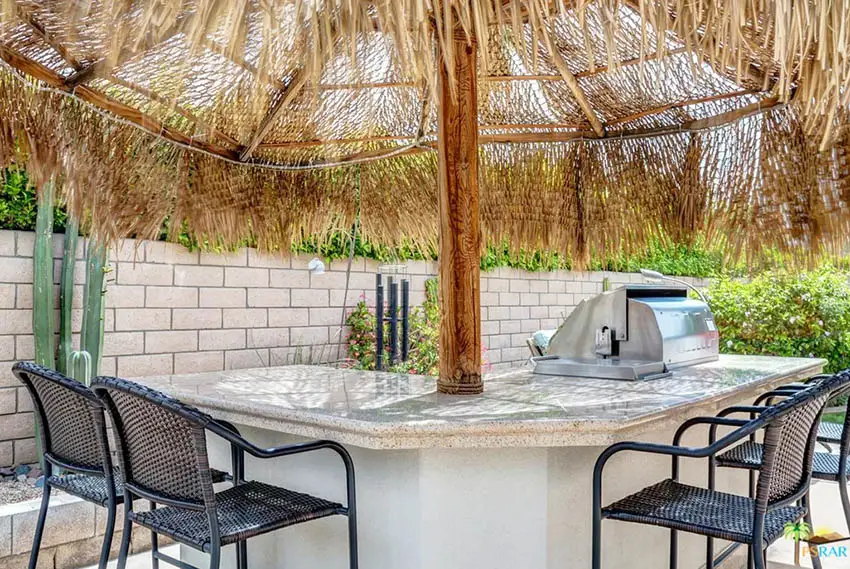 Thatched palapa attached to outdoor kitchen in backyard
