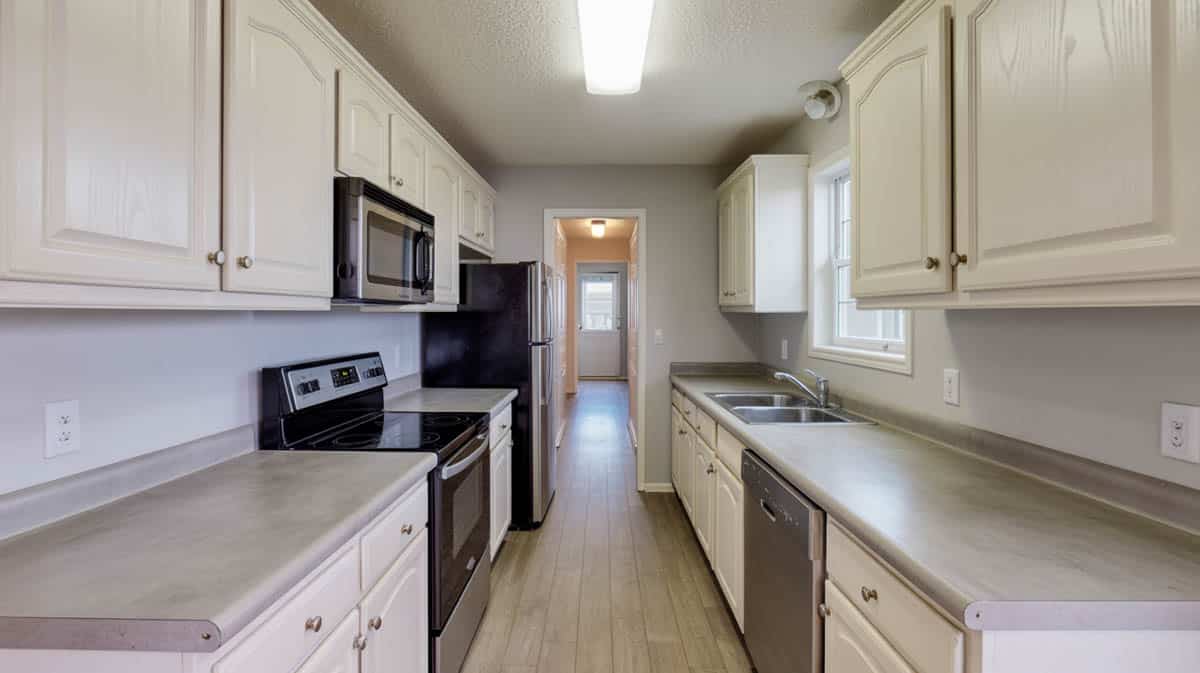 Polished concrete countertop in white raised-panel kitchen with subway tile backsplash