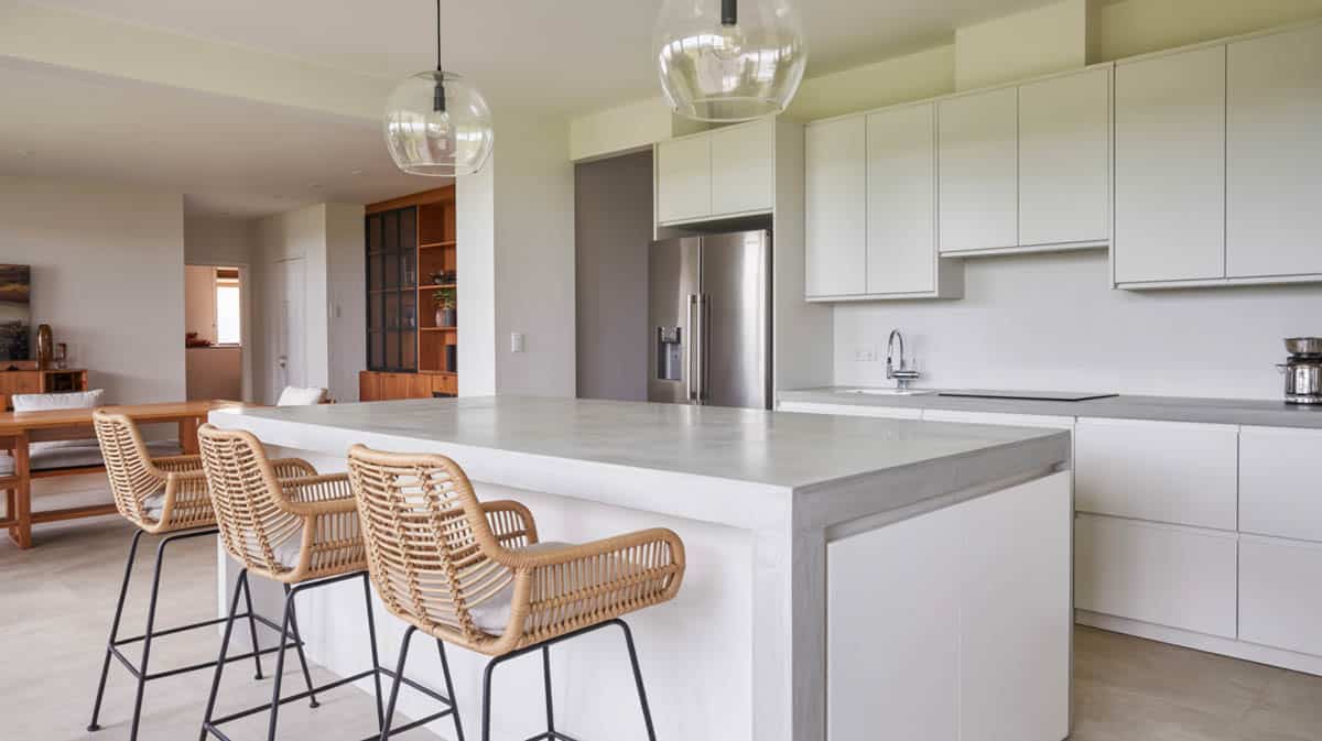 Dark charcoal concrete countertop with black farmhouse apron sink and white shaker cabinets with brass hardware