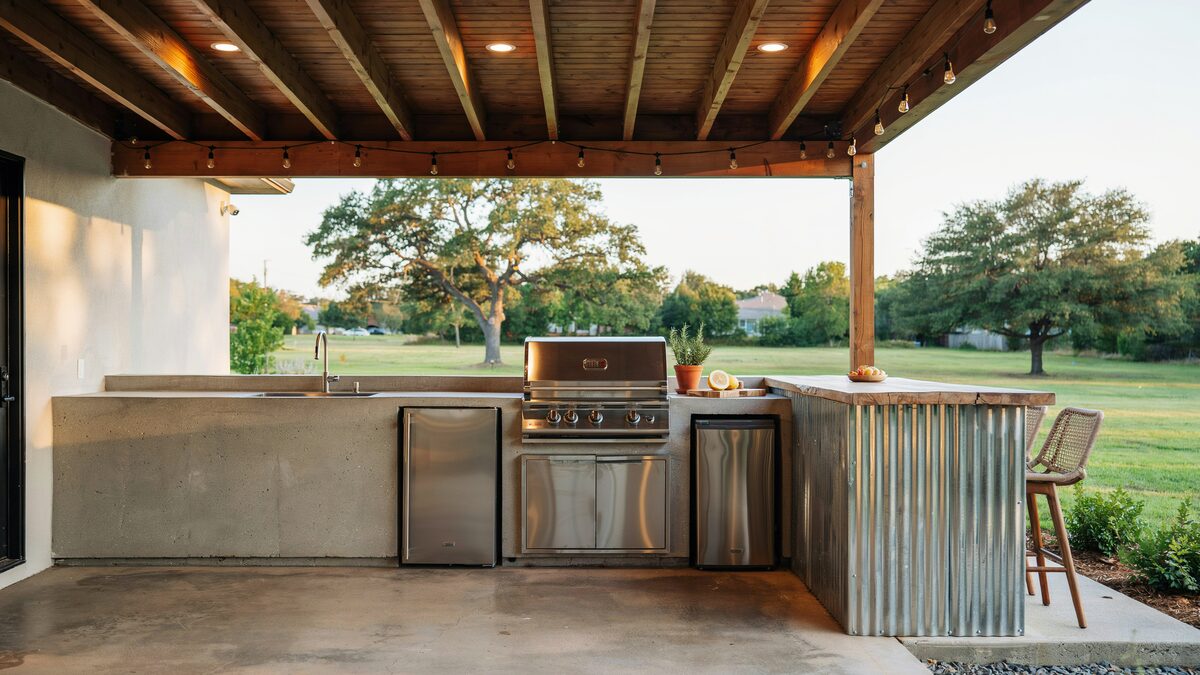 Covered patio kitchen with concrete counter, corrugated metal side island and grill