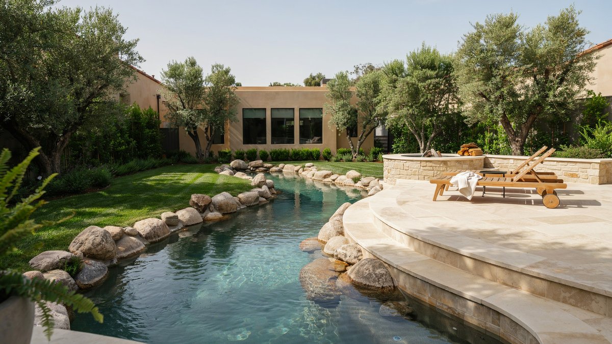 Rock lined lazy river pool circling a luxury home backyard