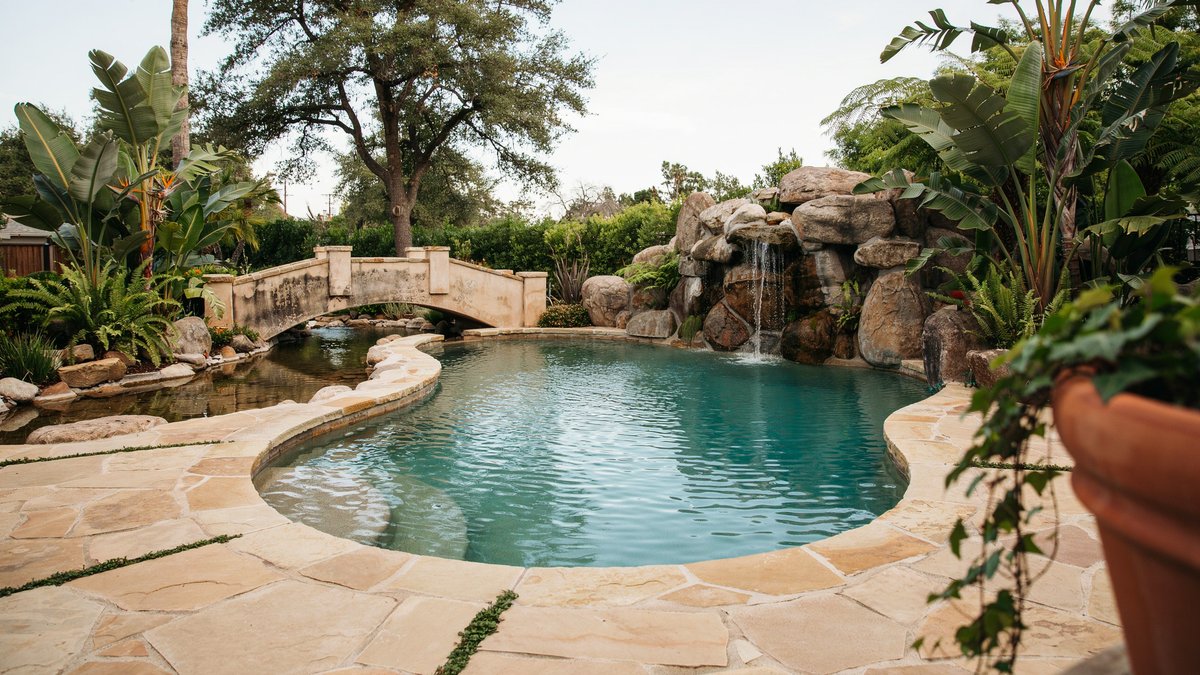 Swimming pool with a rock grotto cave and lazy river bridge