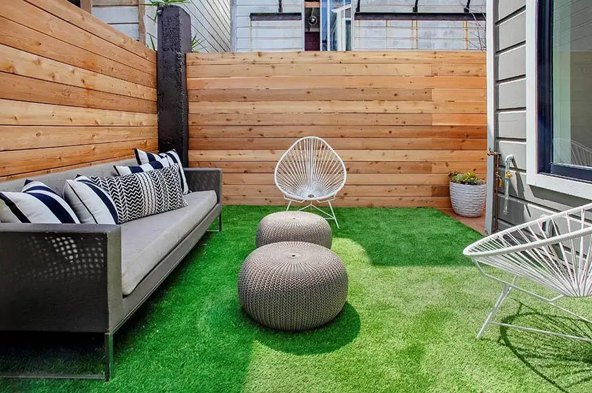 Backyard fenced in patio with artificial grass sitting area