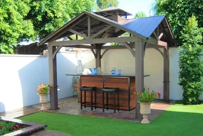 Backyard pavilion with stone patio and artificial grass