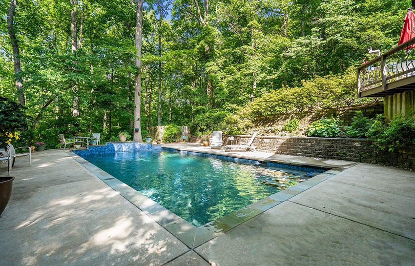 Backyard pool with retaining walls on sloped hill and concrete patio