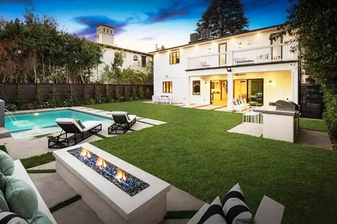 Backyard sitting area with fire pit and artificial grass around pool