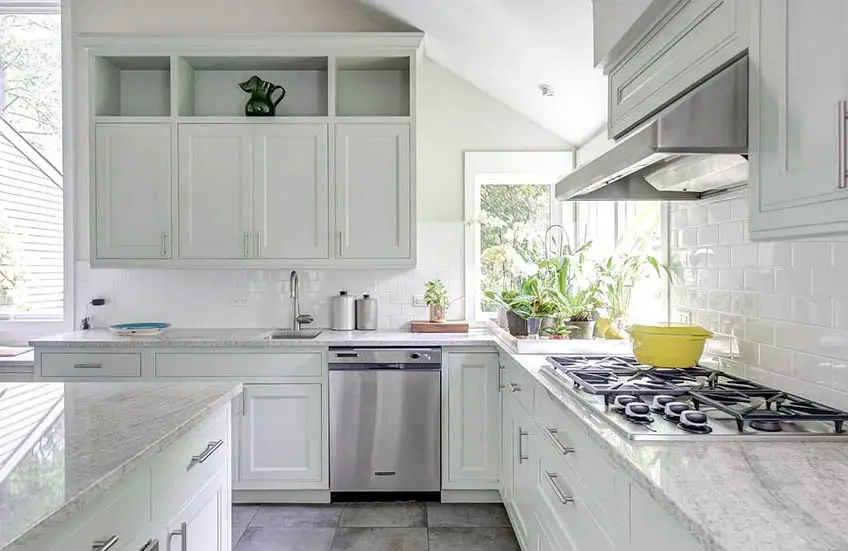 Inviting kitchen with corner window, light green cabinets and white granite countertops