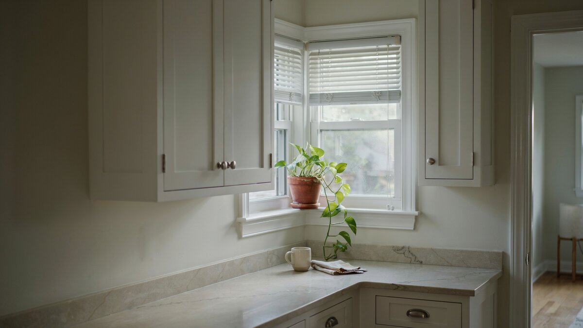 White blinds and a potted plant soften this kitchen corner window