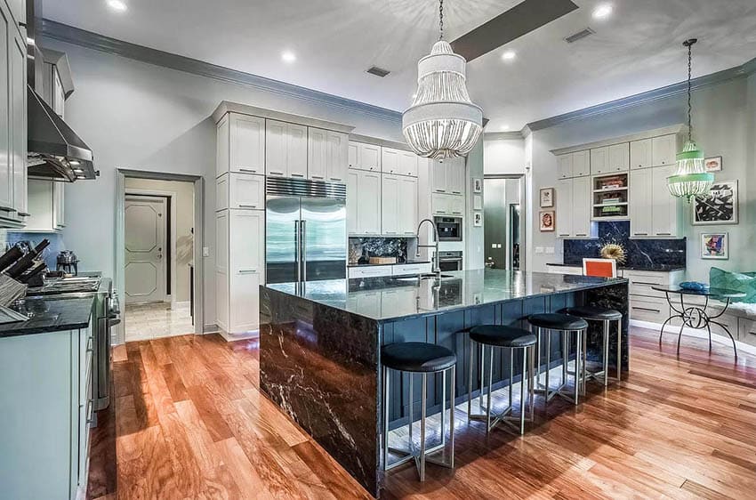 Kitchen with white cabinets black and white quartz countertop waterfall island