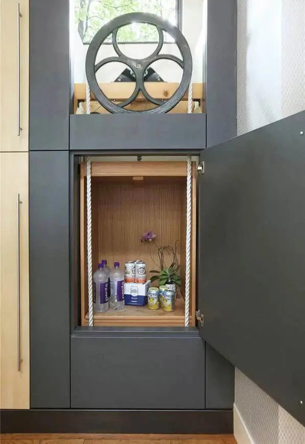 Manual dumbwaiter with large flywheel pulley and rope pulls