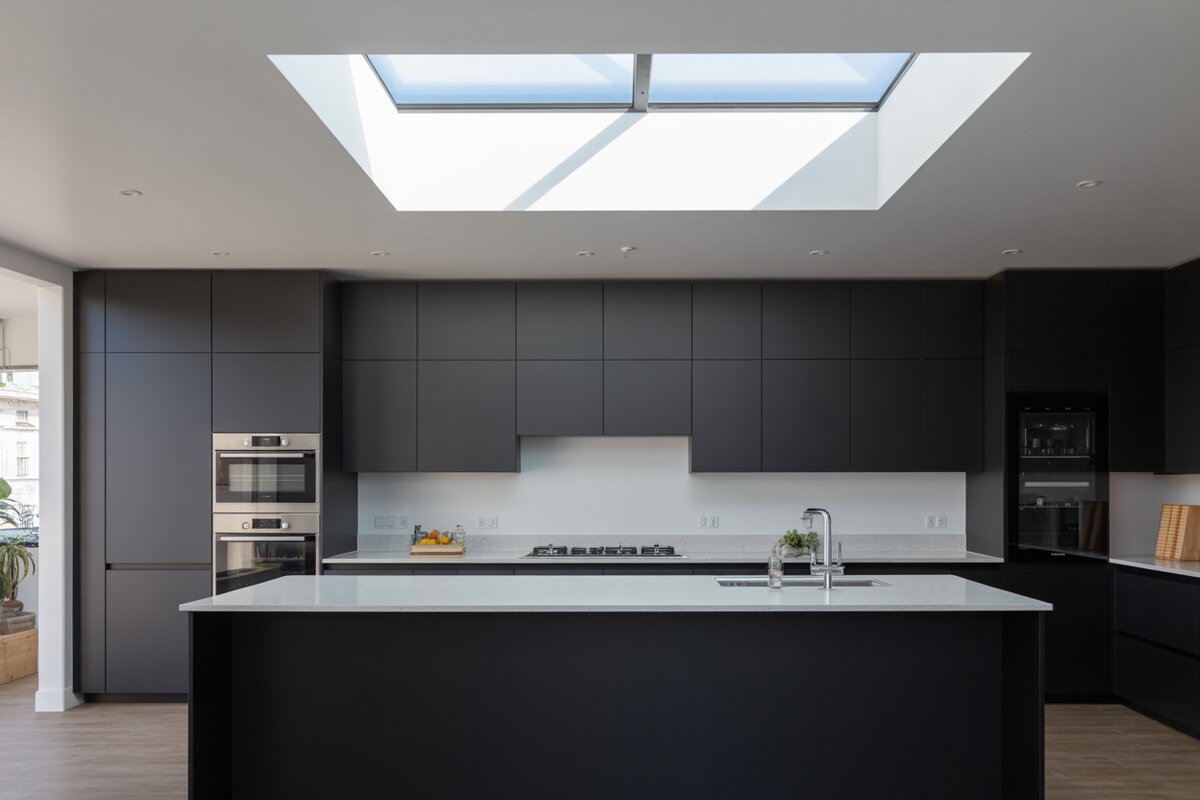 Modern kitchen with matte black cabinets and a large flush ceiling skylight