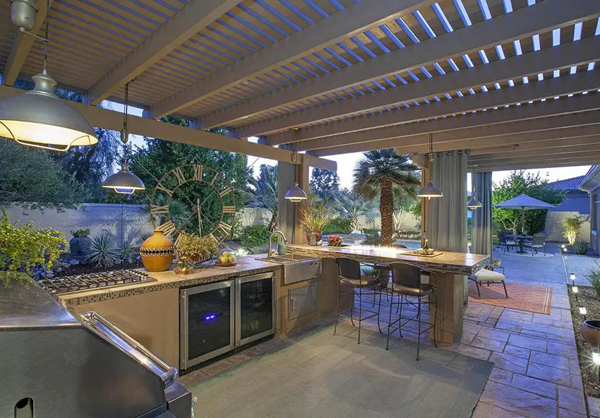 Patio with pergola and outdoor kitchen with concrete counter and mosaic tile sides