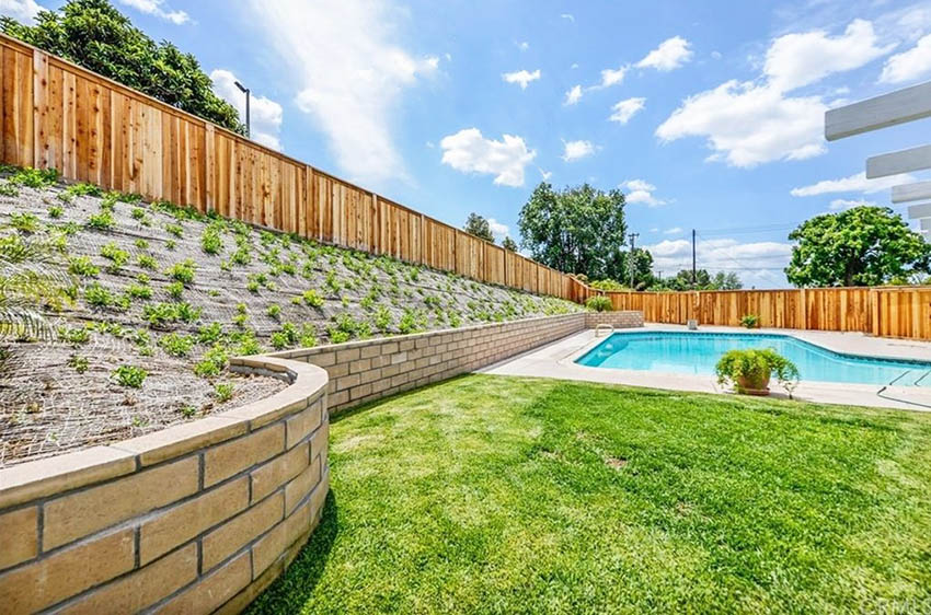 Pool with segmental retaining wall with erosion protection cloth