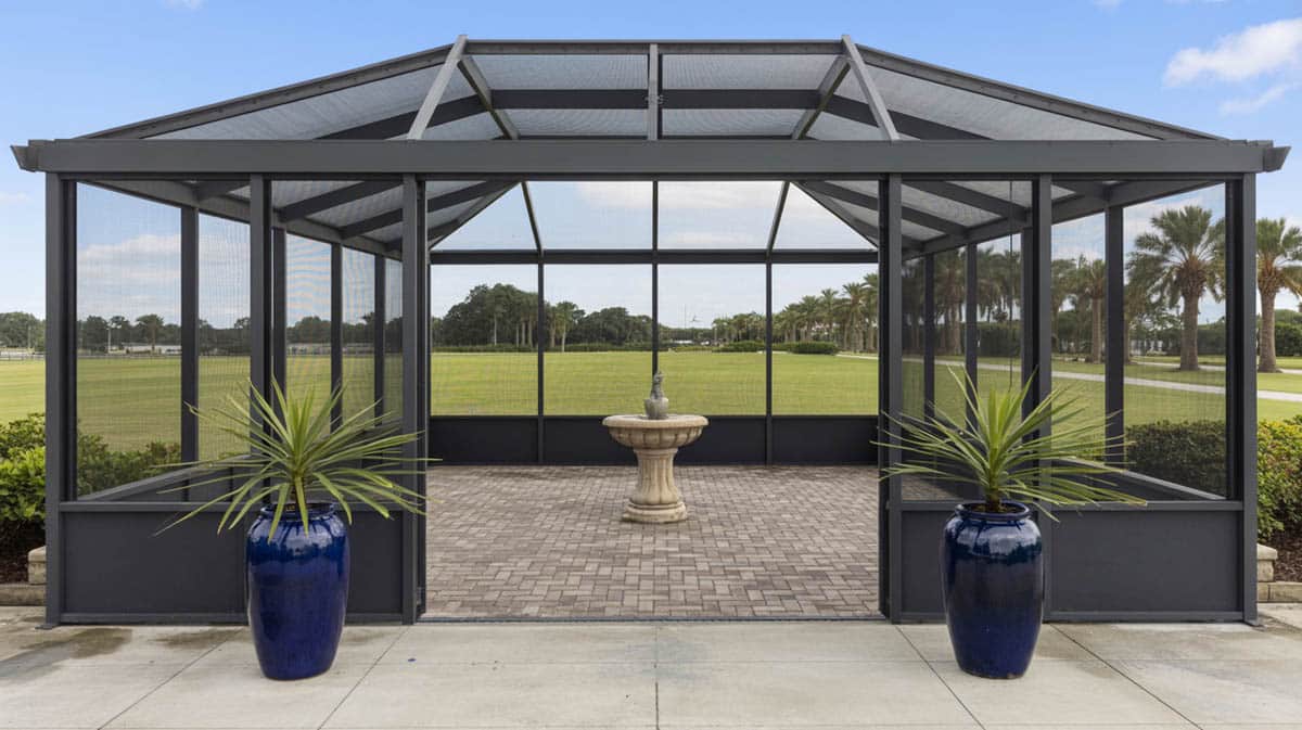Large screen enclosure with dark charcoal frame, stone pavers, cobalt blue ceramic planters, and stone fountain