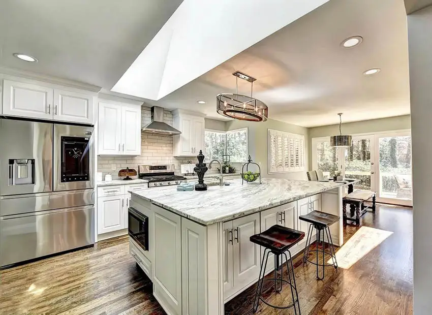 Traditional kitchen with skylight white cabinets and marble countertop island