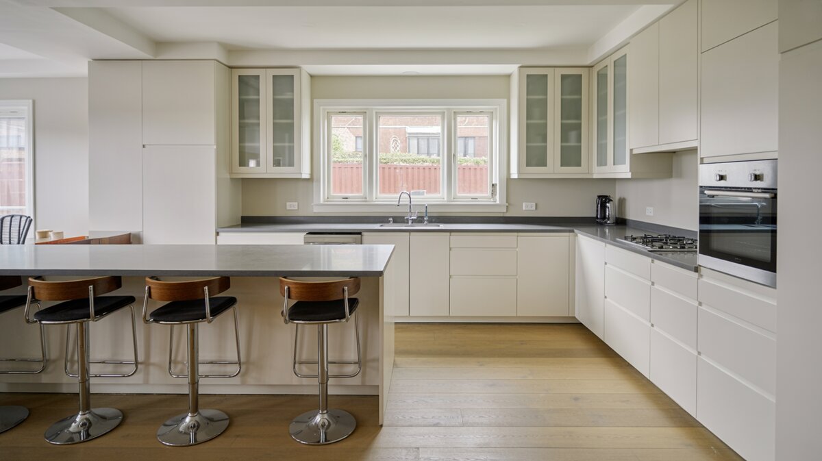 U-shaped modern kitchen with white cabinets and gray countertop pass through window