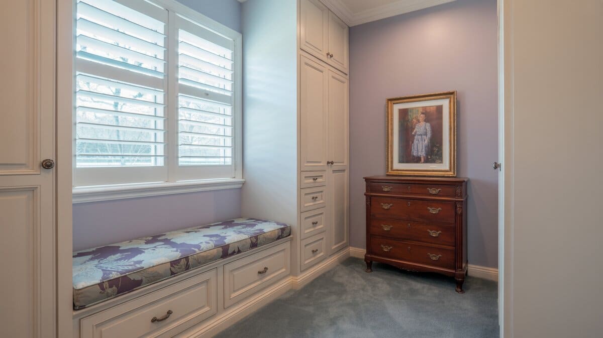 Walk-in closet window bench with drawers and purple cushion under shutters