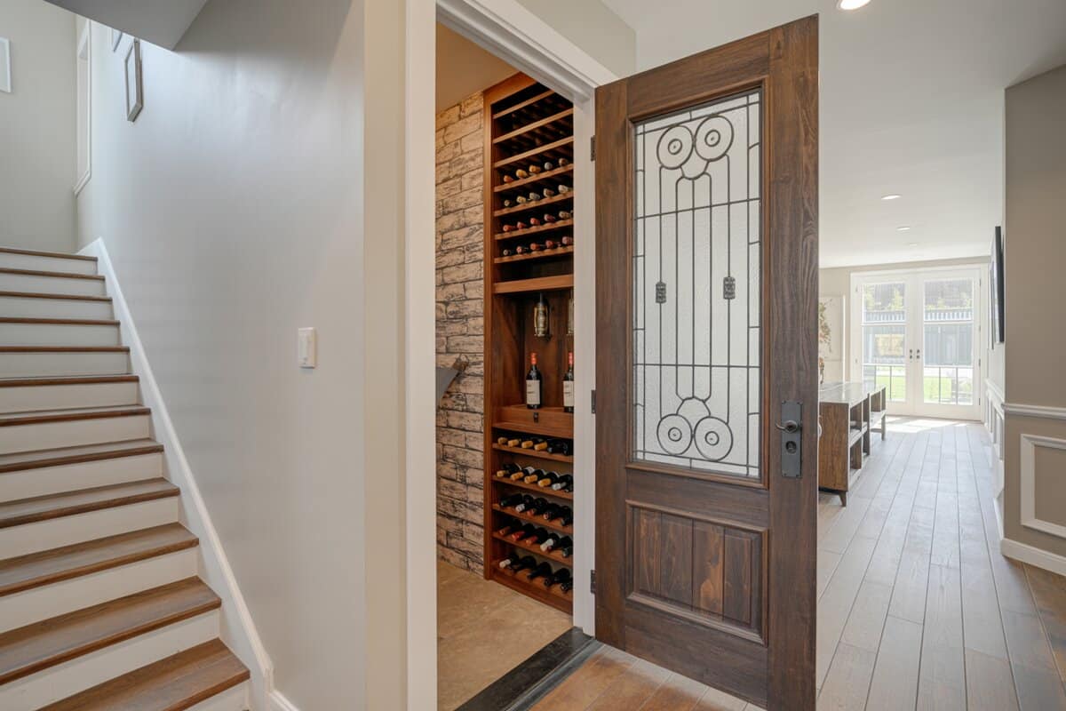 Carved wood door with leaded glass opening to a brick wine nook