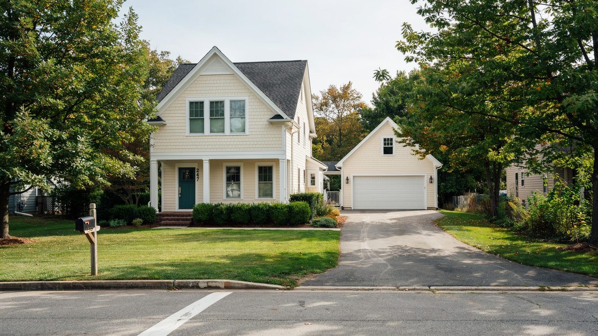 Cream sided house with paved drive leading to a detached garage