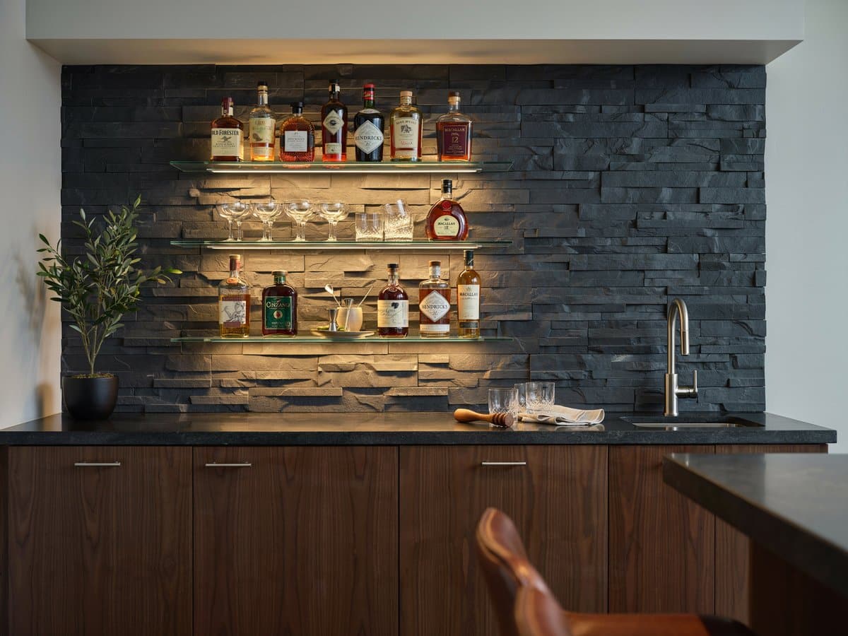 Home wet bar with under shelf lighting glowing on glass shelves and bottles
