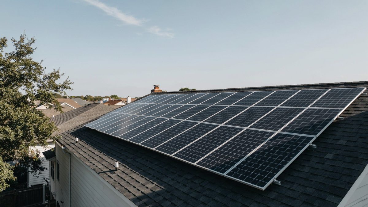Black solar panel array covering the sloped roof of a house