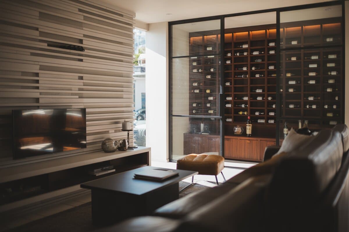 Wood-slat media wall and glass wine room in a leather lounge