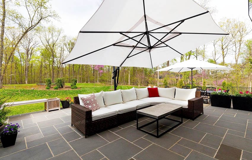 Backyard bluestone pavers patio with large sectional couch and umbrella