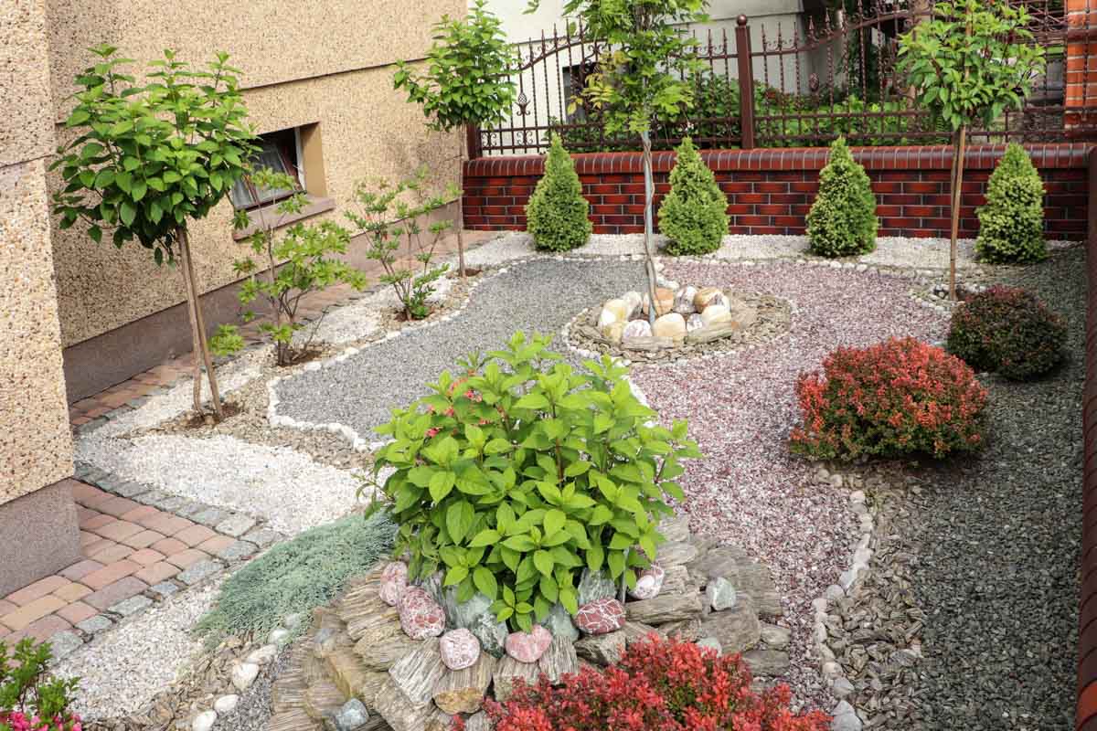 beautiful yard with small trees gravel and fence