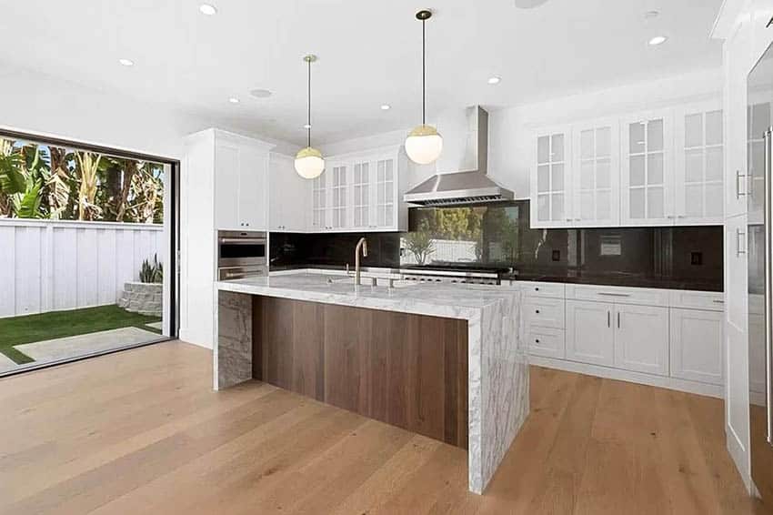 Kitchen with waterfall island and cabinets with glass doors