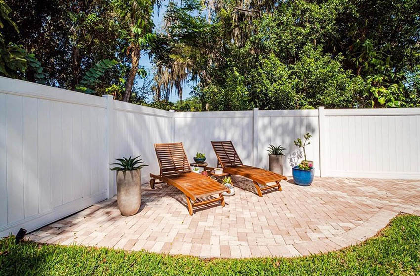 Corner paver patio with white fence